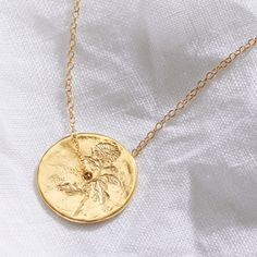 "November birth flower spinner pendant in gold vermeil, delicately hand engraved with a Chrysanthemum flower to symbolise the month of November. This botanical necklace has been handmade in England.  It is hand engraved with a single Chrysanthemum flower and cast in sterling silver, plated with 2.5 microns of 18 carat gold. The gold coin style pendant has a lovely organic texture to the surface to enhance the natural look of the piece. It comes hung on a sterling silver trace chain that has also Elegant Gold Birthstone Necklace With Birth Flower, Gold Flower Pendant Necklace For May Birthstone, Birth Flower Round Disc Necklace For Anniversary, Gold Jewelry With Coin Pendant For May Birthstone, Round Rose Gold Coin Necklace Gift, Anniversary Birth Flower Round Disc Necklace, Yellow Gold Birthstone Charm Necklace With Flower Pendant, Gold Birthstone Necklace With Flower Charm, Gold Birthstone Necklace With Flower Pendant And Charm