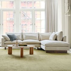 a living room filled with furniture next to large windows and a coffee table in front of the couch