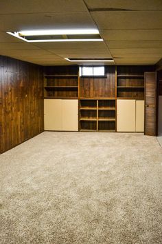 an empty room with wood paneling and carpeted floors is seen in this image