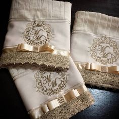 two white towels with gold ribbon and monogrammed initials on them, sitting next to each other