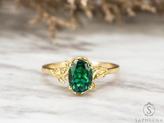 a green ring sitting on top of a white table next to a branch with leaves