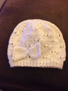 a white knitted hat with a bow on the side sitting on a brown couch