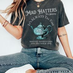 Get ready to be OBSESSED with your new Alice in Wonderland Lewis Carroll Mad Hatter shirt. It's the cutest and most trendy way to combine all those important trendy dark academia and literature shirt vibes! This is the perfect disneyworld shirt!  * Q U I C K * F A C T S * ✺  All shirts are UNISEX ✺  100%  ringspun cotton (fiber content may vary for different colors) ✺  Soft-washed, garment-dyed fabric brings extra coziness ✺  Wash and dry normally (on cool for best results) ✺  Sewn-in twill label * S I Z I N G * ✺ For an oversized fit, select two or three sizes up from your normal size ✺ Model is wearing size L  ✺ Sizing runs true to size ✺ Relaxed fit ✺ Most women find their typical size works best, since they are meant to fit a touch loose ✺ See Size guide and fit in images          * S We're All Mad Here Shirt, Tea Shirts For Women, Alice In Wonderland Tshirts, Alice In Wonderland Shirt Ideas, Themed Cotton Short Sleeve Tops, Themed Graphic Print Short Sleeve Tops, Themed Short Sleeve Top With Graphic Print, Themed Short Sleeve Tops With Screen Print, Themed Cotton Shirt Pre-shrunk