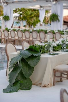 the table is set with white linens and greenery