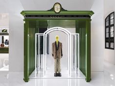 a mannequin is standing in the doorway of a green and white storefront