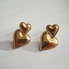 The Double Heart Drop Earrings will add a touch of love to any outfit. With their playful dangle design and bold heart shape, they're the perfect statement earrings for a girls night out or date night. Perfect for anyone who wants to show off their fun-loving side and spread lots of love wherever they go! - stainless steel, gold plated Trendy Heart Charm Earrings For Anniversary, Heart Shaped Metal Earrings For Valentine's Day, Chic Heart Charm Earrings For Valentine's Day, Heart-shaped Metal Earrings For Valentine's Day, Chic Heart Drop Earrings For Anniversary, Chic Heart Shaped Drop Earrings For Anniversary, Trendy Heart Drop Earrings For Anniversary, Trendy Heart-shaped Drop Earrings For Anniversary, Trendy Anniversary Heart Drop Earrings