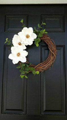 a wreath with white flowers hanging on the front door