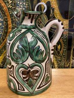 a green and white vase sitting on top of a wooden table