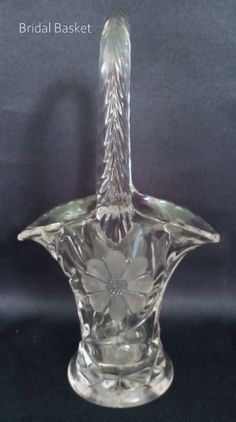 "Product:  Beautiful Floral Cutting with clear glass handled basket with twisted handle and scalloped edge. Egg basket, Candy basket, Flower basket.Centerpiece Approx. measures:  7 ½\"T x 4\" widest point  2 ½\" base Maker Marks:  Brand:  unbranded Color/Material: Clear  Glass Time Period:  before 2000 Country/Region of Manufacture:  ? Condition: Preowned as is. Very good vintage. Glass is bright and shiny.  Damage: No fleabites, cracks, chips, or repairs.   ITEM#DECOR145  Thanks for shopping with ArtisticCollectors Delight Treasure Brokers Curiosity Shop! NOTE: All Vintage items are previously owned \"as is\" & may show some wear or patina with age and crazing and smells/odors. *\"Photos are part of the description\".* Due to lighting effects, monitor's brightness/contrast settings etc, t Bouquet Basket, Basket Centerpiece, Candy Basket, Brides Bouquet, Curiosity Shop, Egg Basket, Vintage Memory