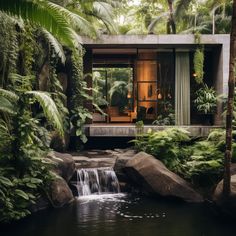 a house in the middle of some trees and water with a waterfall running through it