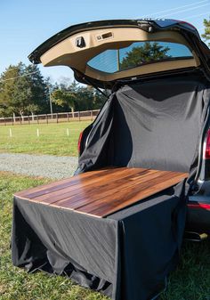 the back end of a car with its trunk open and a wooden table in it