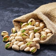 pistachio nuts spilling out of a burlap bag on a slate surface