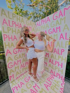 two women standing in front of a large sign that says,'alpha, gaia, and phae