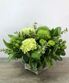 a vase filled with green flowers on top of a wooden table