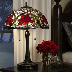 a lamp that is sitting on a table next to a vase with flowers in it