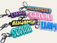 four different colored name tags are shown on keychains with the names of them