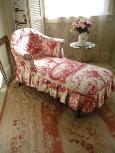 a red and white couch sitting next to a table with flowers on top of it