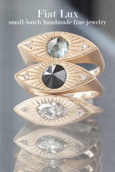 Three yellow gold rings in the shape of an eye stacked on top of each other. The top has a rose cut pale blue Montana sapphire as the pupil, the middle has an inverted black diamond pupil, while the bottom has an antique marquise brilliant cut white diamond pupil. Traditional Engagement Ring, Traditional Engagement, Traditional Engagement Rings, Power Ring, Ring Stack, Montana Sapphire, Gold Ring Stack, Eye Ring