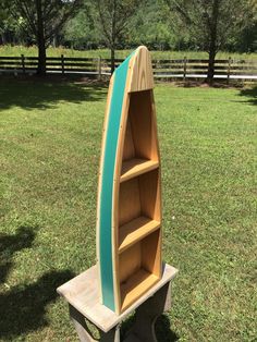 a surfboard shaped bookcase sitting in the grass