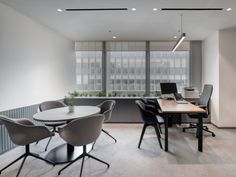 an office with tables and chairs in front of two large windows that look out onto the street