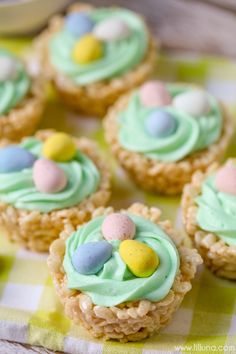 small cupcakes decorated with green frosting and candy eggs on a checkered table cloth