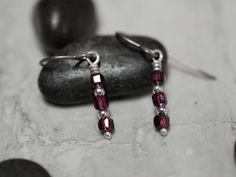 Introducing our stunning silver Dangle Earrings with faceted Garnets, the perfect accessory for adding a touch of elegance to any outfit. These beaded earrings feature genuine natural garnet gemstones that are carefully selected for their stunning color and natural beauty. Crafted from high-quality 999 fine silver, these earrings are hypoallergenic due to their titanium ear wires and suitable for even the most sensitive ears.  I can substitute other ear wire materials upon request, some materials may require an extra charge. Colors: Almandine Garnets: Purple Red These earrings and all of the supplies used in its manufacture are made in the USA.  My gemstones are sourced from an American supplier who utilizes Sustainable Development and Fair Trade practices for all stone sourced from abroad Sterling Silver Faceted Beads Earrings For Gift, Sterling Silver Earrings With Faceted Beads For Gifts, Bronze Bracelets, Almandine Garnet, Geometric Bracelet, Garnet Earrings, Silver Dangle Earrings, Agate Necklace, Delicate Earrings