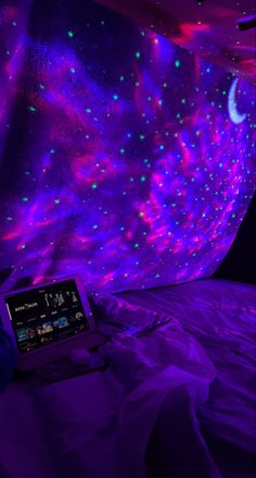 a bed with purple and blue lights in the room, next to a tablet computer