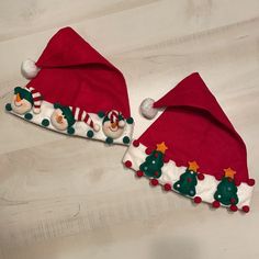 two christmas themed hats sitting on top of a wooden floor with snowmen and trees