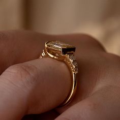 a close up of a person's hand holding a ring with a yellow diamond