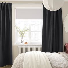 a bedroom with black and white drapes on the windowsill, bed in foreground