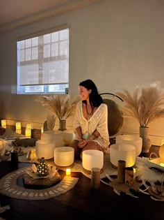 a woman sitting on the floor surrounded by candles