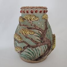 a ceramic vase with leopards on the tree branches and water droplets in its mouth