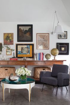 a living room with pictures on the wall and furniture in front of it's glass top coffee table