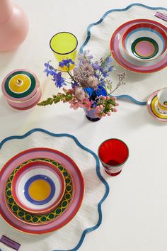 the table is set with colorful plates and vases