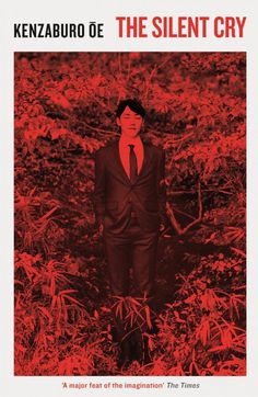 a man in a suit and tie standing in the middle of a field with red leaves