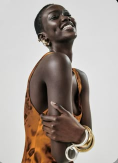 a woman in an orange dress smiling and holding her arms around her neck with both hands