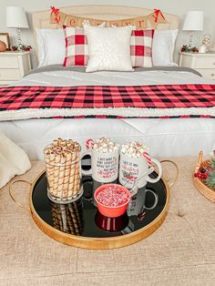 a tray with two mugs and some candy canes on it in front of a bed