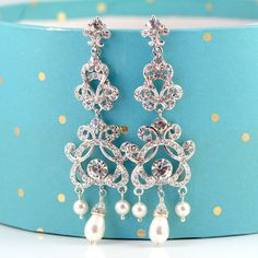 "These glamorous Wedding Bridal Chandelier Earrings feature vintage style Rhinestone components (rhodium plated) encrusted with lots of Swarovski crystals. Accented with Swarovski teardrop pearls, rhinestone drop charms and tiny Swarovski crystals to give a glamorous look. These are 3 1/2\" long and 1 1/4\" (28mm) wide at widest point. These earrings have an exquisite sparkle and are a perfect Wedding accessory. They would also make a glamorous statement to an evening and cocktail party wear! Ma Vintage Silver Crystal Earrings For Wedding, Silver Chandelier Earrings With Rhinestones For Anniversary, Silver Crystal Chandelier Earrings With Elegant Design, Silver Chandelier Earrings With Elegant Crystal Design, Silver Crystal Chandelier Earrings For Wedding, Silver Dangle Bridal Earrings For Wedding, Silver Dangle Crystal Earrings For Wedding, Ornate Silver Chandelier Earrings For Wedding, Ornate Silver Wedding Earrings