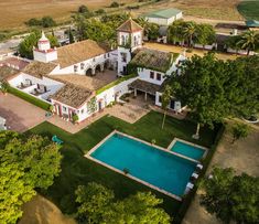 an aerial view of a large house with a pool in the yard and trees surrounding it