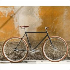 a black and brown bike parked in front of a yellow wall