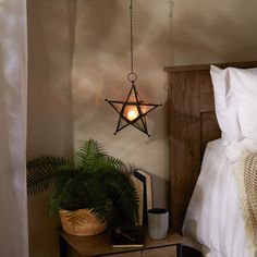 a bed room with a neatly made bed and a star light hanging from the ceiling