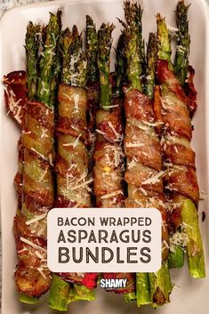 bacon wrapped asparagus bundles in a white dish with a sign that reads bacon wrapped asparagus bundles