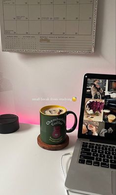 an open laptop computer sitting on top of a white desk next to a cup of coffee