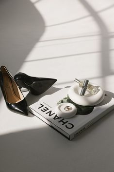 a pair of black high heel shoes sitting on top of a book next to a pair of heels