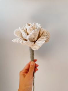 a hand holding a flower that is knitted to look like it's blooming