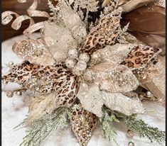 a close up of a flower on top of a white table cloth with gold and silver decorations