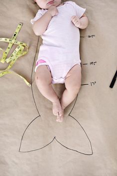 a baby laying on top of a sheet of paper next to a tape measure line