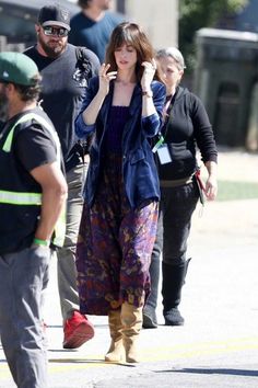 a woman is walking down the street talking on her cell phone while others look on