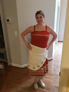 a woman in a red tank top and white skirt standing with her hands on her hips