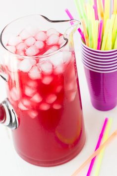 a pitcher filled with liquid next to two cups full of straws